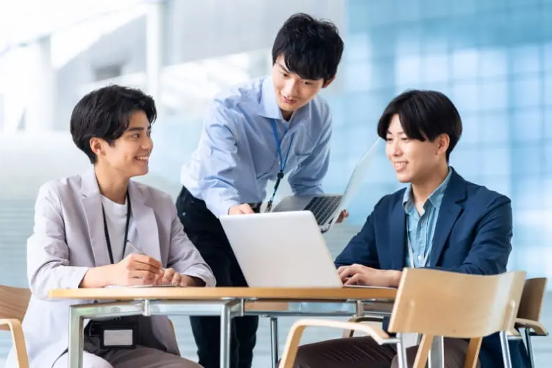 オフィスの明るい空間で打ち合わせをする3人の男性の写真