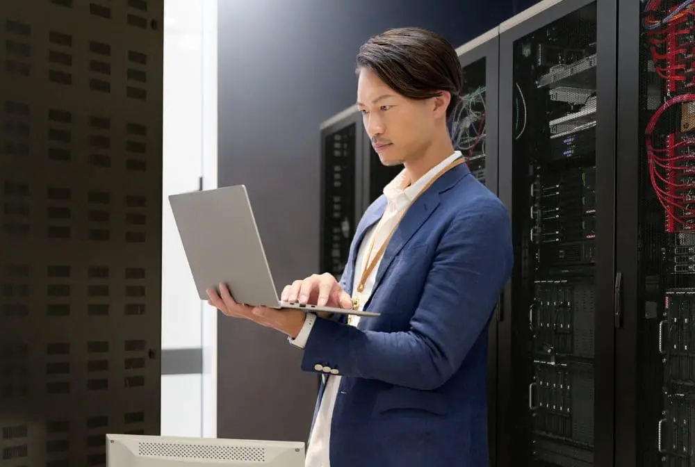 サーバールームでノートパソコンを操作する男性エンジニア