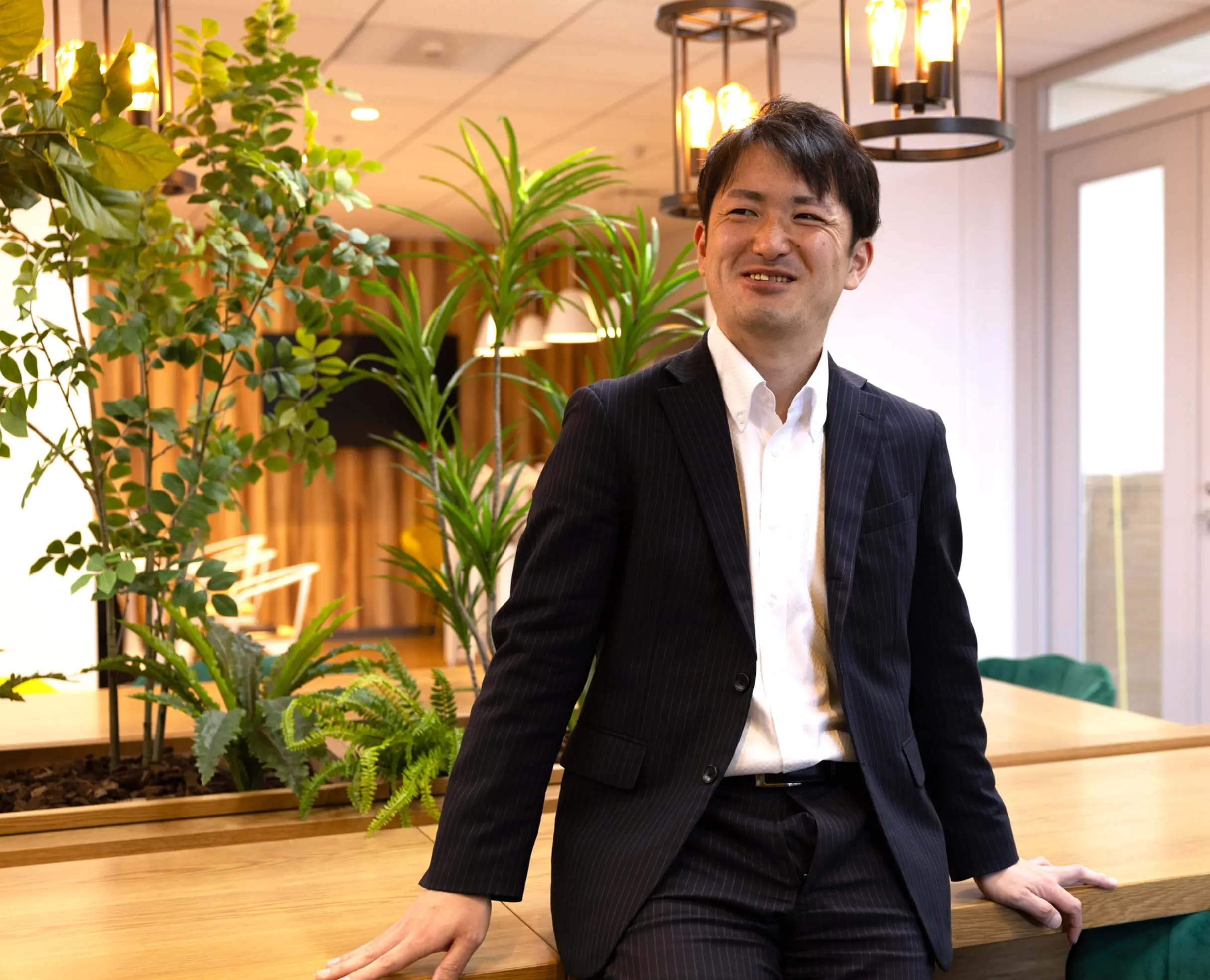 観葉植物のあるオフィスで笑顔の男性社員